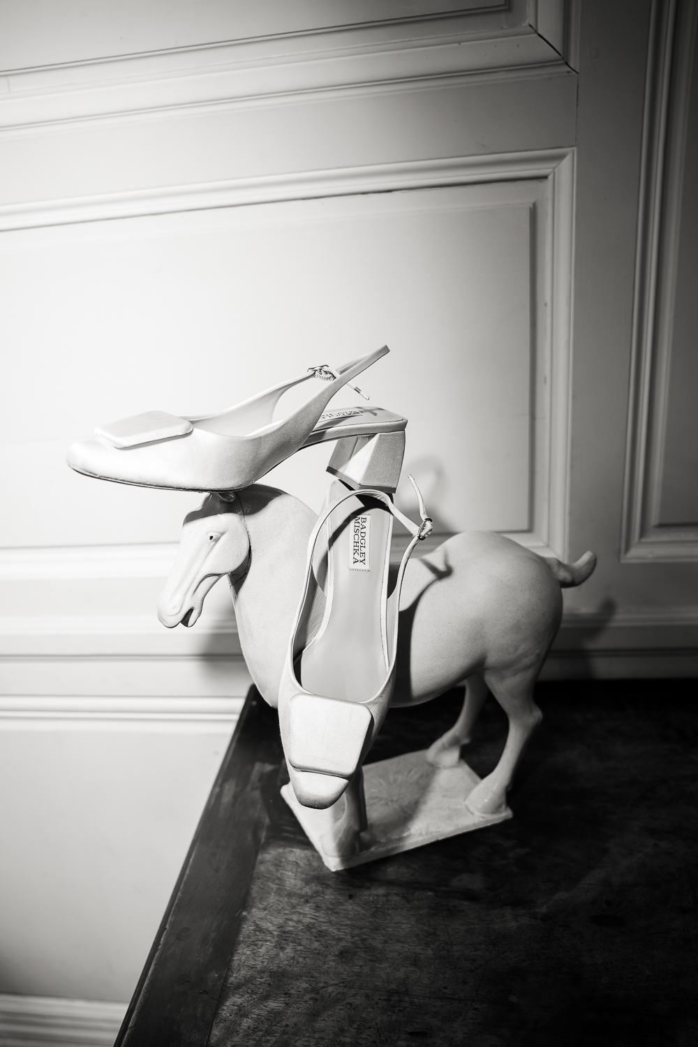 White satin heels rest on a sculptural ceramic animal, creating a refined still life that highlights elegant wedding details before the celebration.